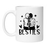 Biały kubek z napisem BESTIES i grafiką dwóch bliskich sobie dziewczyn